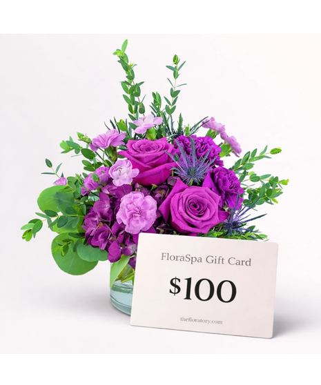 magenta flowers with green filler around them in a low glass container