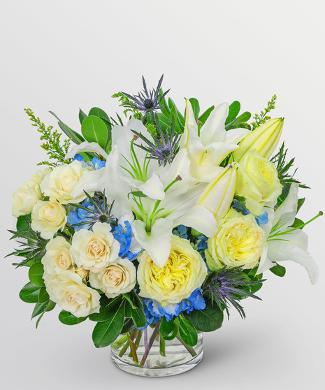 white yellow and blue flowers in a low clear vase